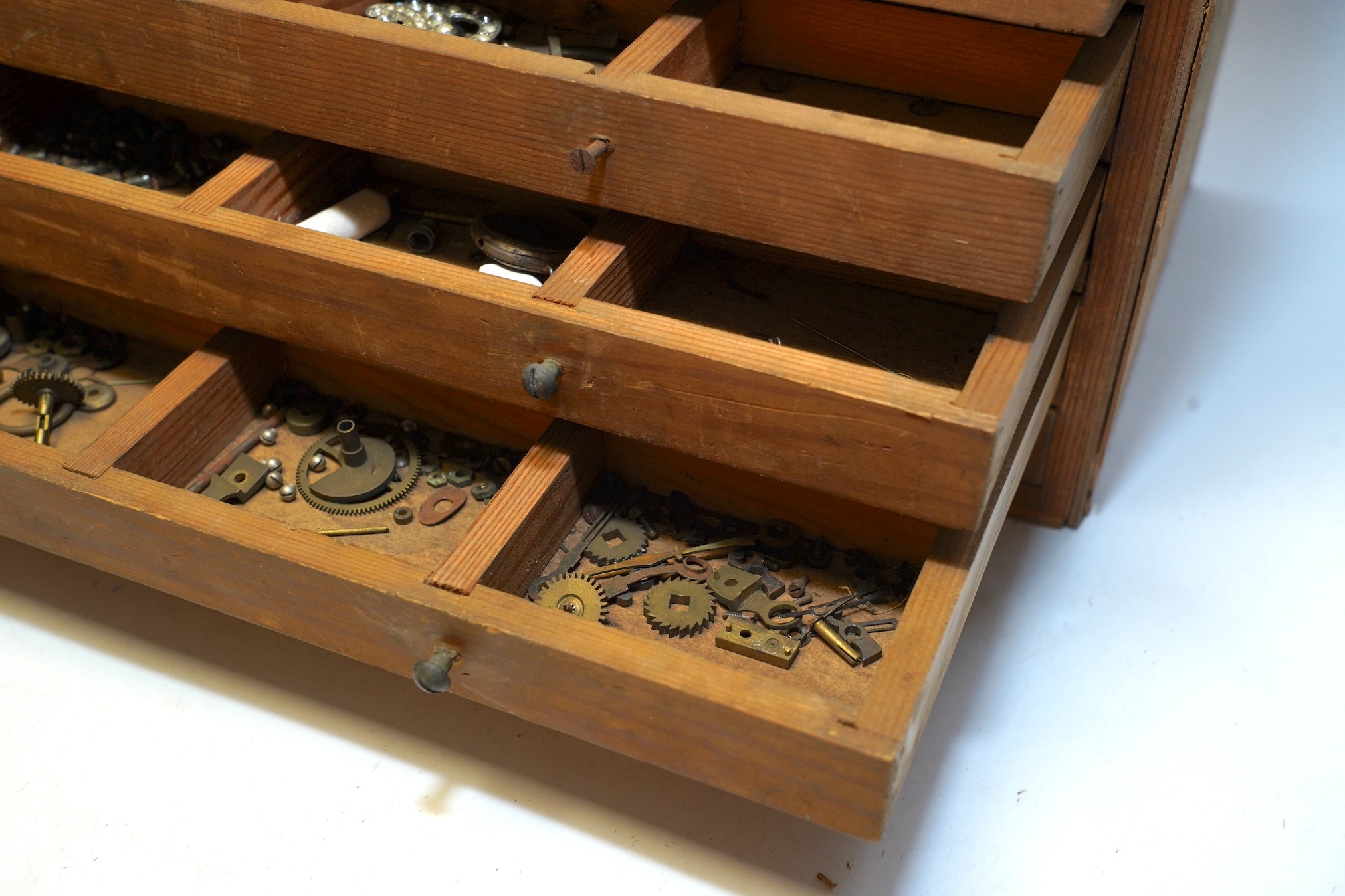 A wooden twelve drawer cabinet containing a collection of watch parts. Condition - cabinet fair to good, watch parts as found